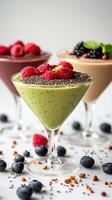 Colorful dessert cups filled with creamy delights topped with fresh berries and chia seeds on a light backdrop photo