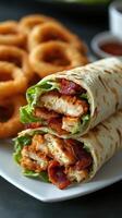 Delicious chicken and bacon wraps served with crispy onion rings on a plate in a cozy dining setting photo