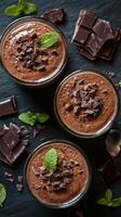 Smooth and rich chocolate mousse served in elegant glasses with fresh mint and chocolate shavings on a dark surface photo