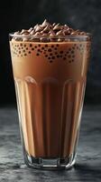 Creamy chocolate drink topped with whipped cream sits in a clear glass on a dark surface during the evening photo