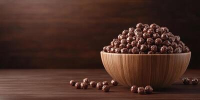 Chocolate-covered snacks in a wooden bowl placed on a rustic wooden table photo
