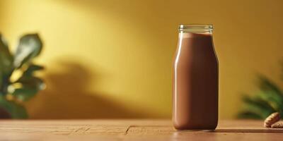 Milk bottle filled with chocolate drink on wooden table against yellow background in a cozy setting photo
