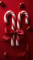 Festive candy canes tied with a red ribbon surrounded by shiny ornaments on a bright red background photo