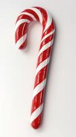 Handmade red and white striped candy cane displayed on a plain background during the holiday season photo