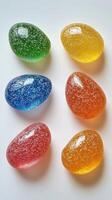 Colorful gelatin eggs with sparkling texture displayed on a white surface in bright lighting photo