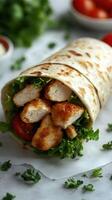 Freshly made chicken wrap with crisp lettuce and ripe tomatoes served on a marble countertop photo