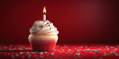 Sweet birthday cupcake with candle glowing brightly against a red background surrounded by colorful sprinkles photo