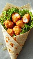 Crispy chicken bites wrapped in a tortilla with fresh lettuce and a light drizzle of sauce photo