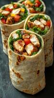 Grilled chicken wraps filled with fresh vegetables and herbs served on a dark stone background photo