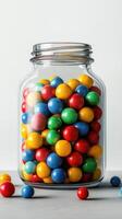 Colorful gumballs in a glass jar create a vivid display on a minimalist surface in bright lighting photo