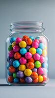Colorful candy coated gumballs vibrantly displayed in a glass jar on a neutral background photo