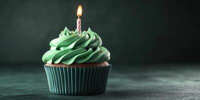 Cupcake with green frosting and a candle ready for celebration in a dimly lit setting photo