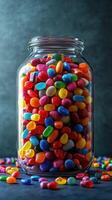 Brightly colored candy fills a large glass jar on a dark background, showcasing various shapes and hues photo