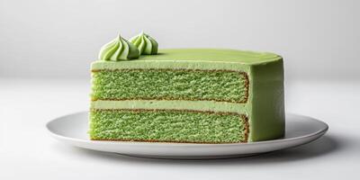 Moist green tea cake with smooth frosting and decorative swirls on top displayed on a white plate photo
