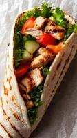 Grilled chicken wrap with fresh vegetables served on a rustic background photo