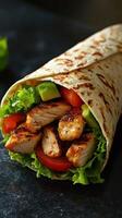 Delicious grilled chicken wrap with fresh vegetables served on a dark surface photo