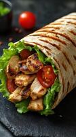 Grilled chicken wrap with fresh vegetables and herbs on a dark background photo