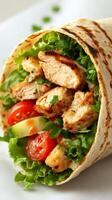 Delicious grilled chicken wrap filled with fresh vegetables and herbs on a light background photo