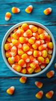 Colorful candy corn in a bowl on a vibrant blue wooden surface during autumn festivities photo