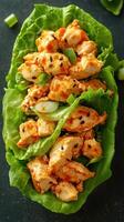 Crispy chicken dish garnished with green onions served on fresh lettuce leaves with sesame seeds photo