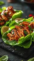 Grilled chicken lettuce wraps served with lime and garnished with fresh herbs on a black stone surface photo