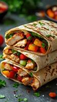 Delicious grilled chicken wraps filled with fresh vegetables and herbs on a dark stone countertop photo