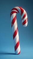 Vibrant candy cane with red and white stripes standing alone against a blue background photo