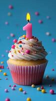 Colorful cupcake with a pink candle for a first birthday celebration on a blue background photo