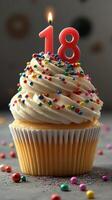 Colorful cupcake with eighteen birthday candle topped with sprinkles for celebration at a festive party setting photo