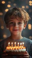 Boy celebrates birthday with cake and candles glowing in soft ambient light during a festive evening gathering photo
