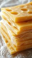 Stacked slices of yellow cheese wrapped in clear film ready for sandwiches and snacks at a kitchen counter photo