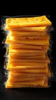 Slices of yellow cheese stacked in plastic wrap on a dark background creating a vibrant culinary display photo