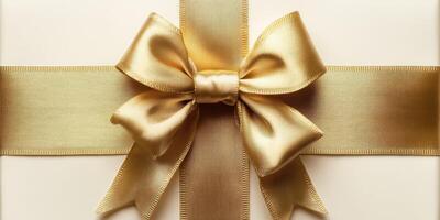 Elegant gift wrapped in cream-colored paper with a shiny gold bow showcased against a neutral background photo