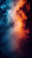 Colorful smoke swirling in contrasting hues of blue and orange against a dark backdrop in a creative setting photo