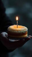 Celebrate with a beautifully frosted cake featuring a lit candle held in a person's hand during an evening gathering photo
