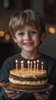 Smiling child holds a birthday cake with candles at a cozy indoor celebration in the evening photo