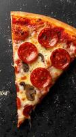 Slice of pepperoni pizza with mushrooms on a dark surface ready to be enjoyed for lunch or dinner photo