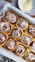 Freshly baked cinnamon rolls covered with icing on the table video