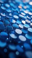 Blue metallic coins arranged closely, reflecting light and creating a textured pattern of shine and depth across the surface photo