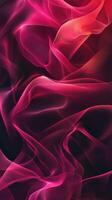 Abstract swirling patterns of vibrant pink and red flowing fabric against a dark background photo