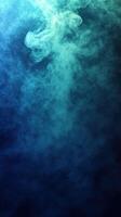 Colorful smoke swirls create an abstract design in a dark environment with blue and green tones photo