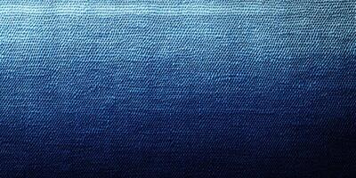 Textured fabric with a gradient from light blue to deep navy blue showing intricate weaving patterns under soft lighting photo