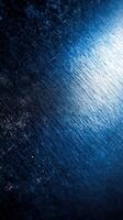 Textured blue metallic surface with shining highlights and subtle patterns during late evening light photo