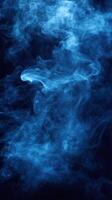 Ethereal blue smoke swirls creating an enchanting atmosphere in a dark setting photo