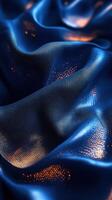Beautiful blue fabric draping elegantly with shimmering gold accents in soft waves photo