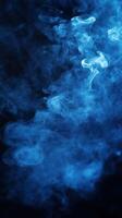 Blue smoke swirling in dark background creating an ethereal and mysterious atmosphere photo