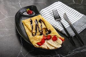 A plate with a crepe and strawberries on it photo