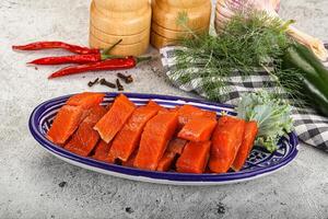 A plate of sliced salmon and vegetables on a table photo