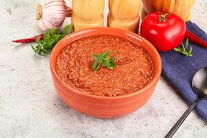 A bowl of tomato soup with a spoon and a knife photo