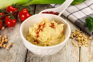 A bowl of hummus with some vegetables and spices photo